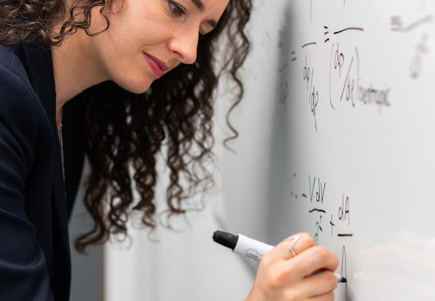 woman writing formula on whiteboard
